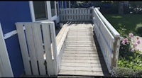 a wooden bench on a wooden deck next to a house