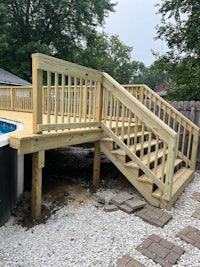 a wooden deck with stairs leading to a swimming pool