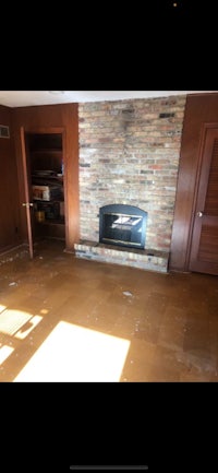 an empty living room with a brick fireplace