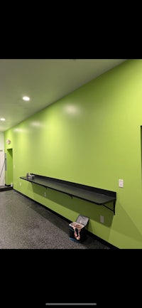 a gym with a green wall and a bench