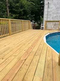 a wooden deck next to a swimming pool