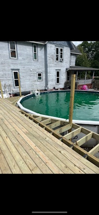 a pool with a wooden deck and a green pool