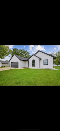 a home with a garage in the middle of a grassy field