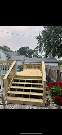 a wooden deck with stairs leading to a pool